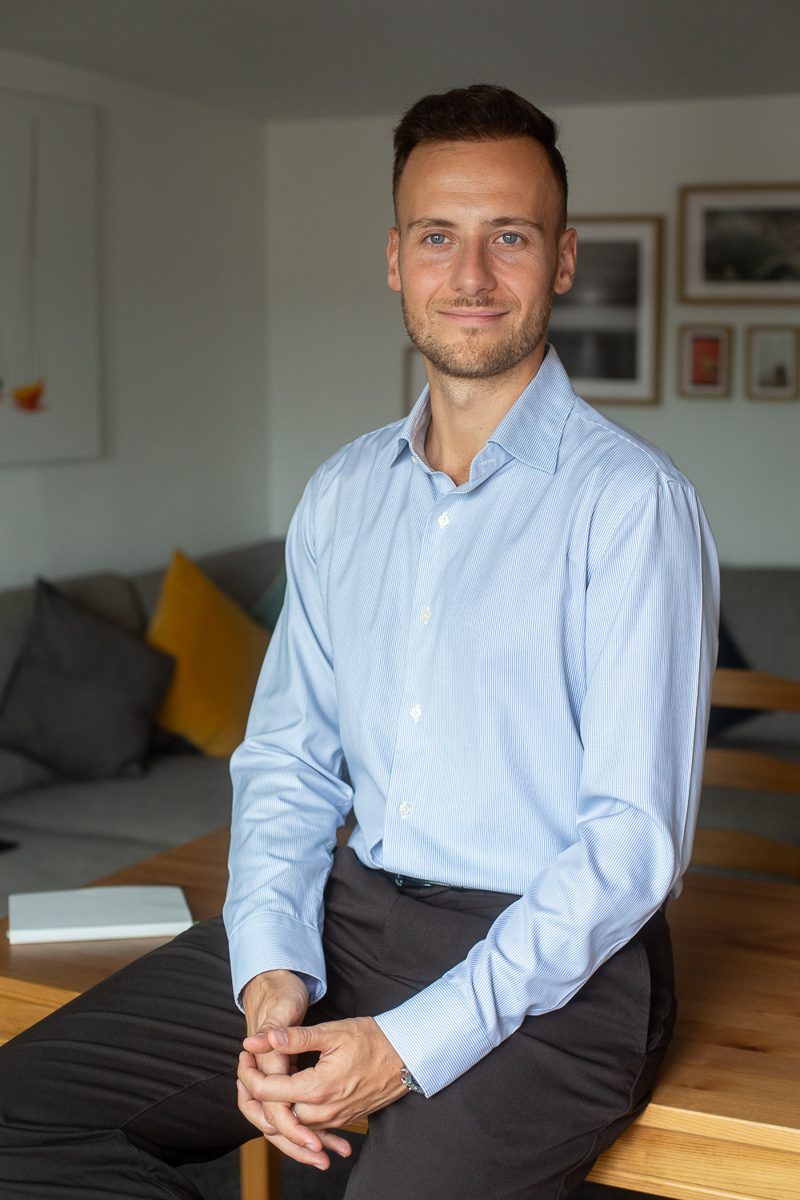 Dorian López sentado en una mesa de madera, con camisa azul